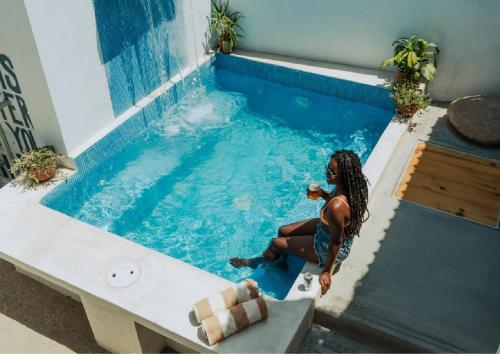 a woman sitting in a swimming pool at Outsite Todos Santos - Formerly Perro Surfero Hotel Boutique in Todos Santos