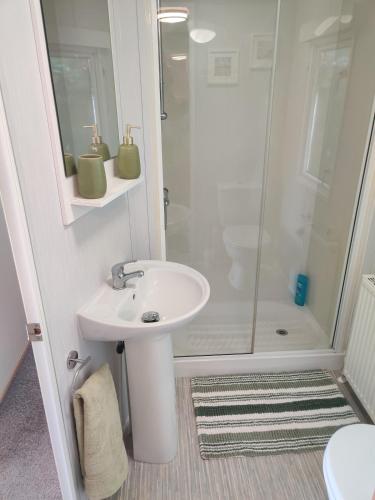 a white bathroom with a sink and a shower at Maggie's Garden Retreat in Millom