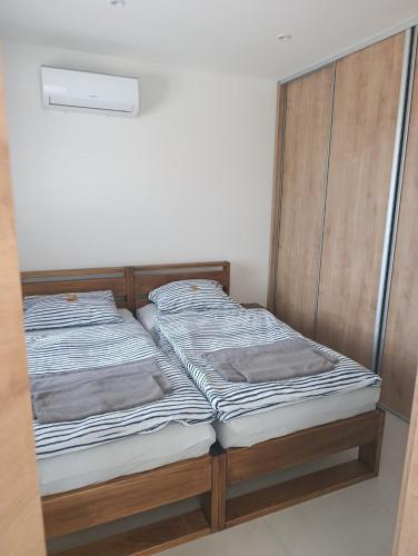 two beds in a bedroom with a wooden headboard at Apartmány Nitrianska osada in Bánov