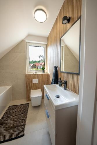 a bathroom with a sink and a toilet and a mirror at Osada Wiśniewo in Płótowa