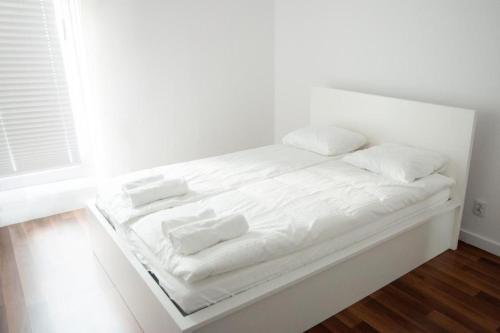 a white bed with white sheets and pillows on it at Apartament Verde in Łódź