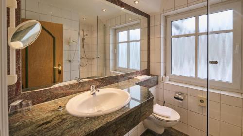 ein Badezimmer mit Waschbecken, Toilette und Spiegel in der Unterkunft auswärts - Dein Hotel in Schmallenberg