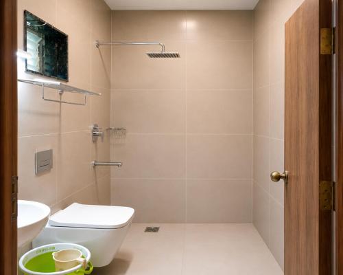 a bathroom with a shower and a toilet and a sink at Hotel Lemon in Valavanūr