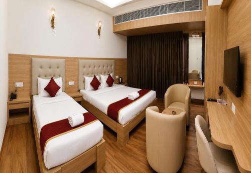 a hotel room with two beds and a tv at Hotel Lemon in Valavanūr