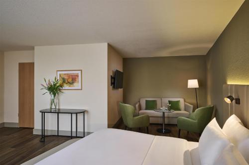 ein Hotelzimmer mit Bett, Stühlen und Sofa in der Unterkunft NH Leipzig Messe in Leipzig