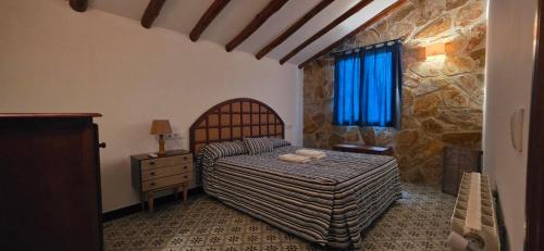 a bedroom with a bed and a stone wall at Casas Rurales Cortijos el Encinar in Torres