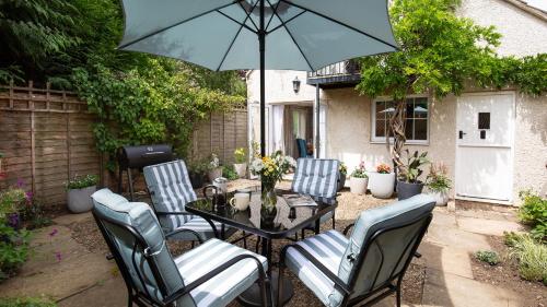 a patio with a table with chairs and an umbrella at Lemon Tree Cottage in Broadway