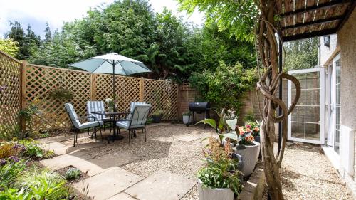 a patio with a table and chairs and an umbrella at Lemon Tree Cottage in Broadway