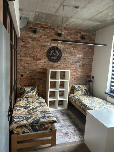 a bedroom with two beds and a brick wall at Noclegi Kolejowa in Rybnik