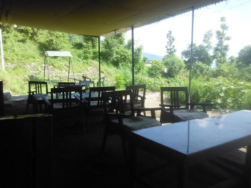 a group of tables and chairs in a room with a window at Rishikesh Valley in Rishīkesh