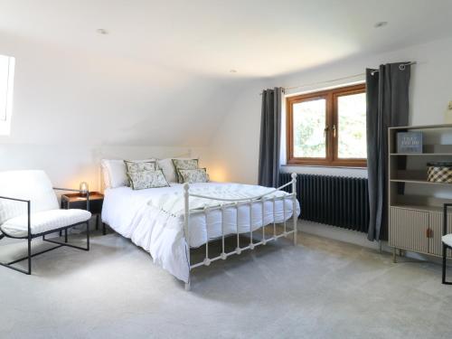 a bedroom with a bed and a chair and a window at Barn Owl Cottage in Bedford