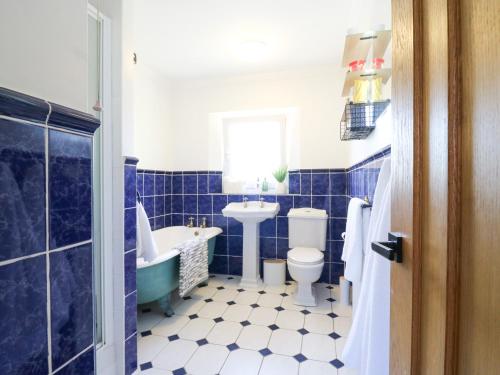 a blue and white bathroom with a tub toilet and sink at Barn Owl Cottage in Bedford