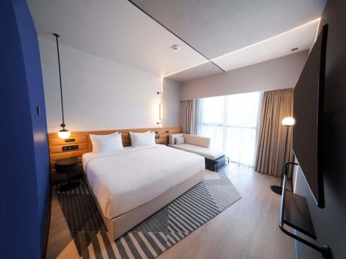 a hotel room with a white bed and a television at Novotel Madinah in Medina