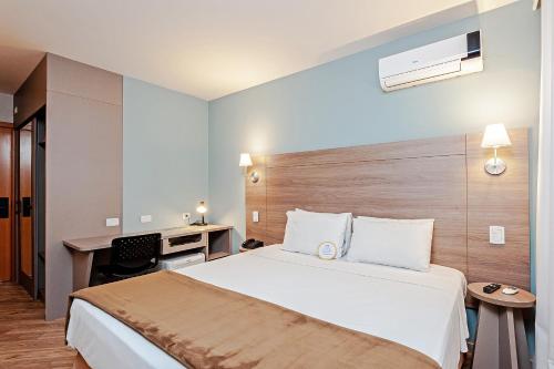 a hotel room with a bed and a desk at Slim Hotel Curitiba Alto da XV in Curitiba