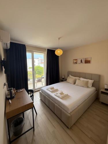 a bedroom with a bed and a table and a window at Къща Грийн Хаус in Chernomorets