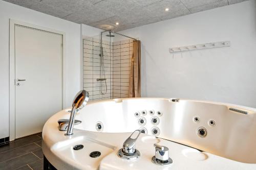 a bathroom with a tub and a sink at Activity House With Wellness Area-Sj700 in Thyborøn
