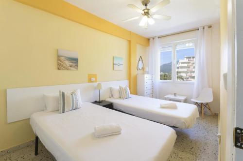 two beds in a room with a window at Abaco in Playa de Xeraco