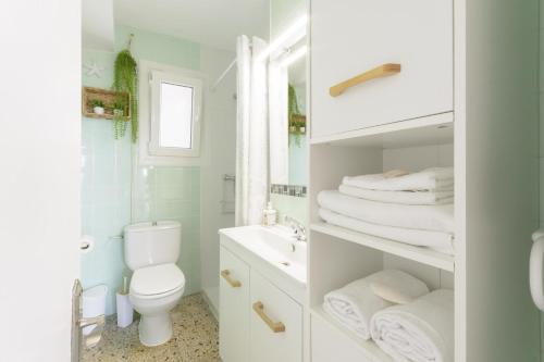 a white bathroom with a toilet and a sink at Abaco in Playa de Xeraco