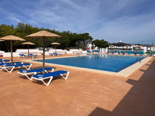 a swimming pool with lounge chairs and umbrellas at Camping La Aventura Playa in Daimuz