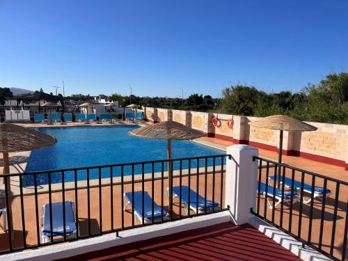 a balcony with chairs and umbrellas next to a swimming pool at Camping La Aventura Playa in Daimuz