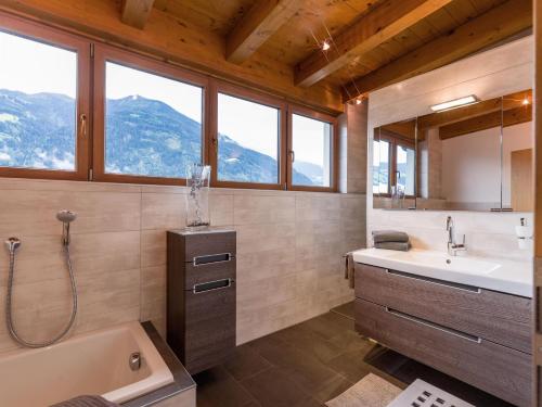 a bathroom with a tub and a sink and windows at Ferienwohnung Schwarzenauer in Fügen