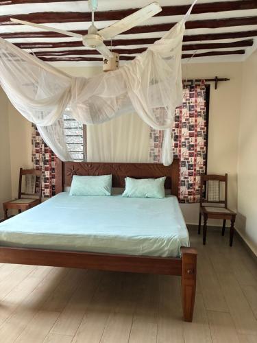 a bedroom with a bed with a mosquito net at Lions Home in Diani Beach