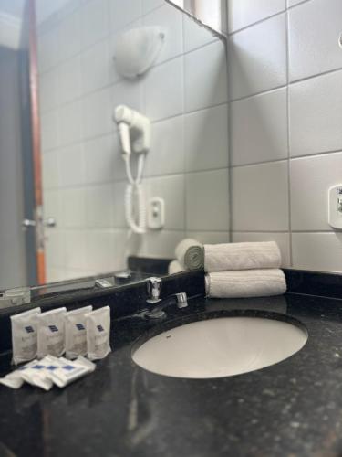 a bathroom with a sink with a mirror and a phone at Praia Hotel Enseada in Maceió