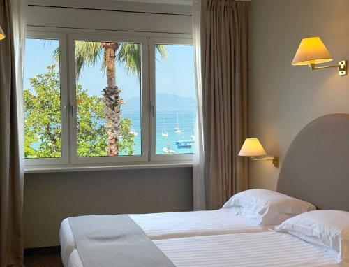 a hotel room with two beds and a palm tree at Hotel Nettuno in Bardolino