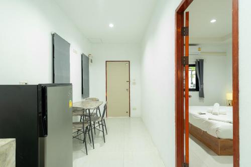 a room with a bed and a table and a refrigerator at Malinee Resort in Bang Tao Beach