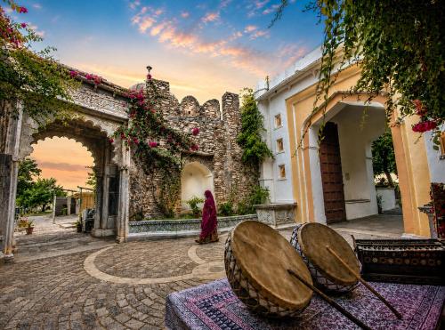a woman in a red dress standing outside a building at Castle Bijaipur - A Luxury Heritage Resort, Chittorgarh in Bijaipur