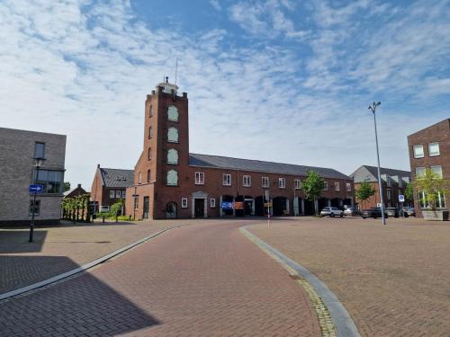 a brick building with a clock tower on a street at De Oude Brandweerkazerne 2 tot 4 persoons 2 kamer appartement in Kaatsheuvel
