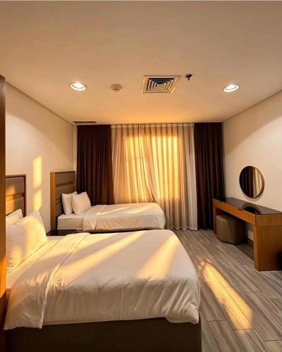 a hotel room with two beds and a desk at فندق بلازا أثينيه Plaza Athenee Hotel in Kuwait