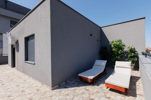a patio with two lounge chairs and a building at Aqua Studios with Spa & Free Parking in Jagodina