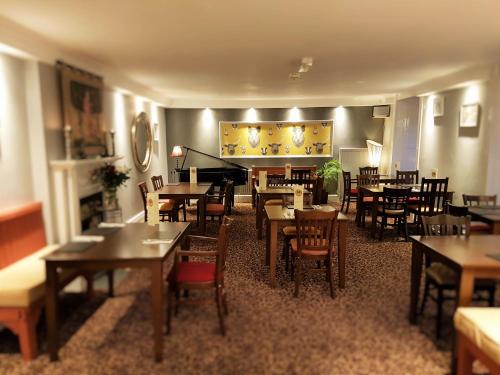 a restaurant with tables and chairs and a piano at Dunster Castle Hotel in Dunster