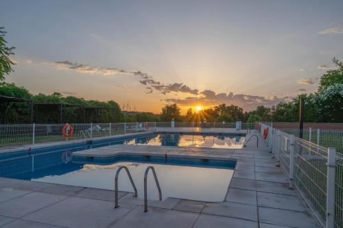 a swimming pool with a sunset in the background at Exe Zarzuela Park in Madrid