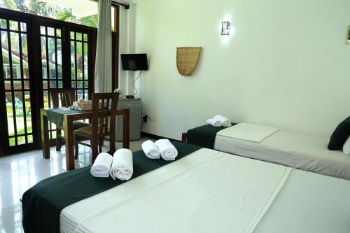 a hotel room with two beds and a table with a chair at Kyo Garden Villa in Negombo