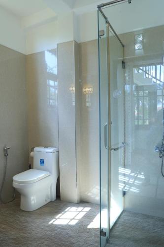 a bathroom with a toilet and a glass shower at Kyo Garden Villa in Negombo