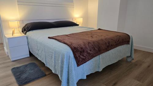 a bedroom with a bed with a blue blanket and a night stand at Loft Casco Viejo 4 in Ourense