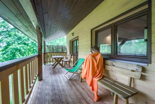a woman sitting on a bench on a porch at Agroturystyka Wesoła Chmura - dom w Masywie Śnieżnika in Kletno