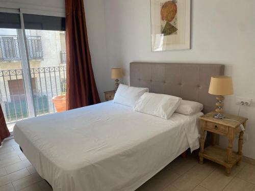 a bedroom with a white bed with a window at Mandala apARTments, confort y encanto a pie playa in Calafell