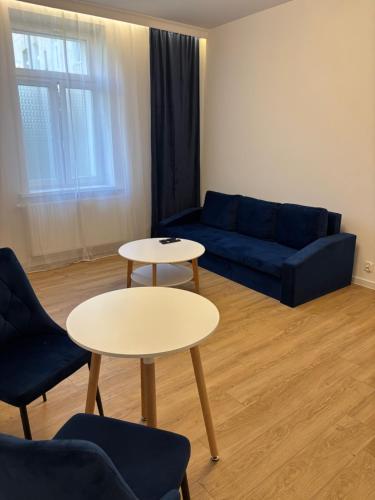 a living room with a blue couch and two tables at JD Apartment Sobieskiego in Gniezno