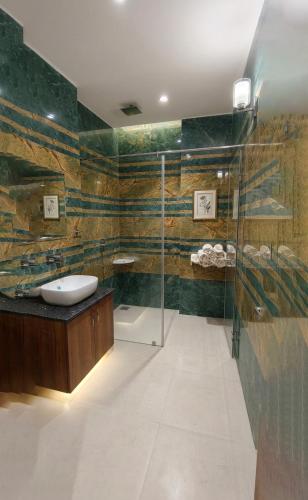 a bathroom with a glass shower and a sink at Hotel Kanak in Gangānagar