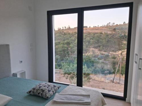a bedroom with a bed and a large window at Quinta das Reveladas in Marvão