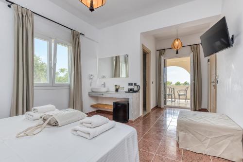 a white bedroom with two beds and a television at Armeno Resort in Marathias
