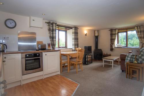 a kitchen and living room with a table and chairs at Lake View - Old Mill Cottages in Ilfracombe