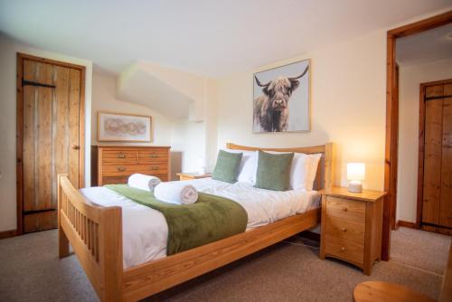 a bedroom with a bed with a cow picture on the wall at Lake View - Old Mill Cottages in Ilfracombe
