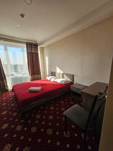 a hotel room with a bed and a desk and a chair at Harmony Inn in Almaty