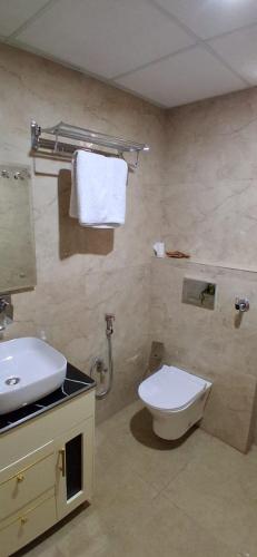 a bathroom with a white toilet and a sink at Hotel Silver Oak in Dehradun