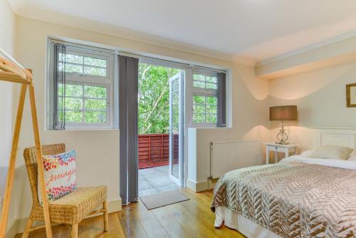 a bedroom with a bed and a chair and windows at Redhill town centre apartments by Livingo in Redhill