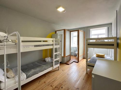 a small room with two bunk beds and a desk at A Beira Hostel in Aveiro
